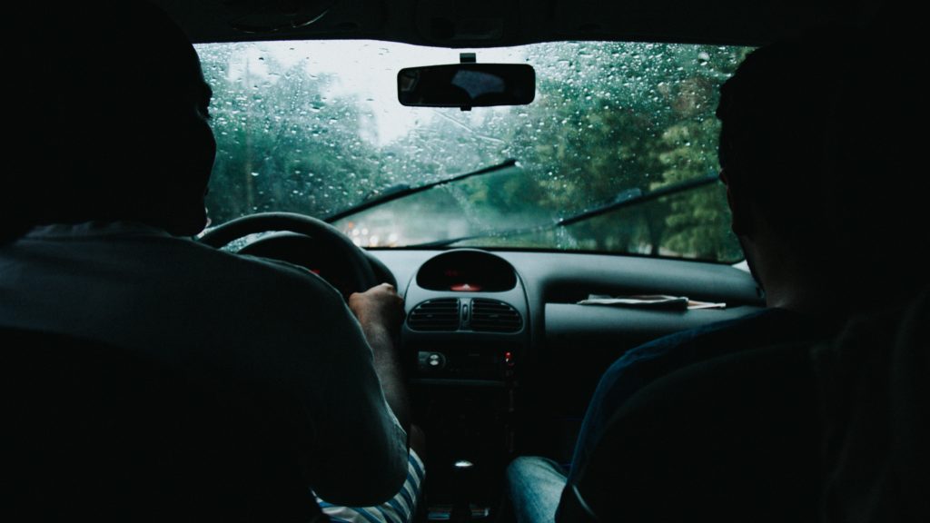 The interior of a car shot from the backseat. It's a grey wet day. 