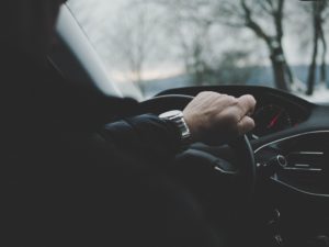 Man's hand on steering wheel of car