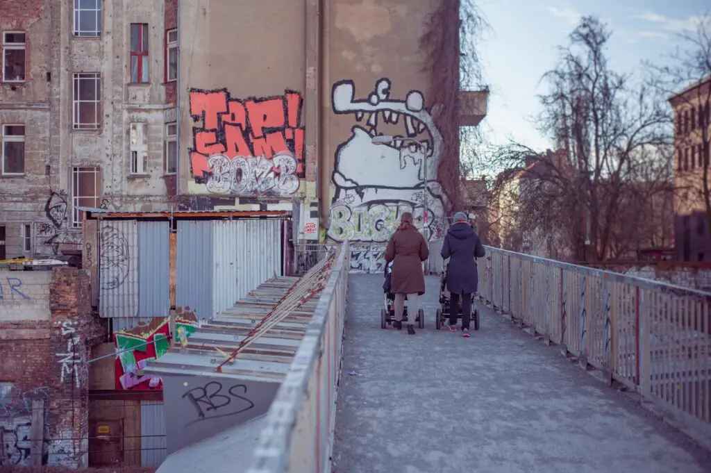 women pushing cat strollers over an urban bridge